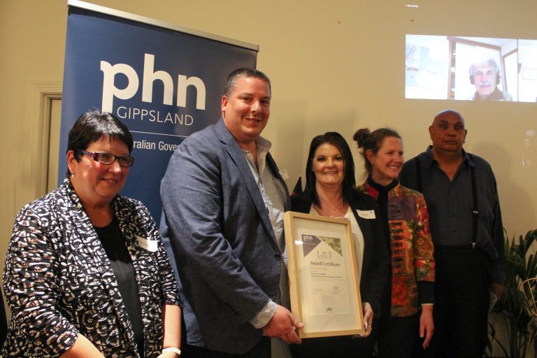 A group of people receiving an award in front of a PHN banner