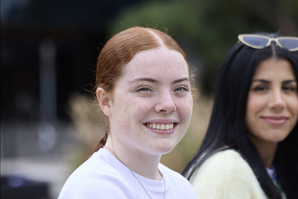 A young person with long red hair in a pony tile smiling