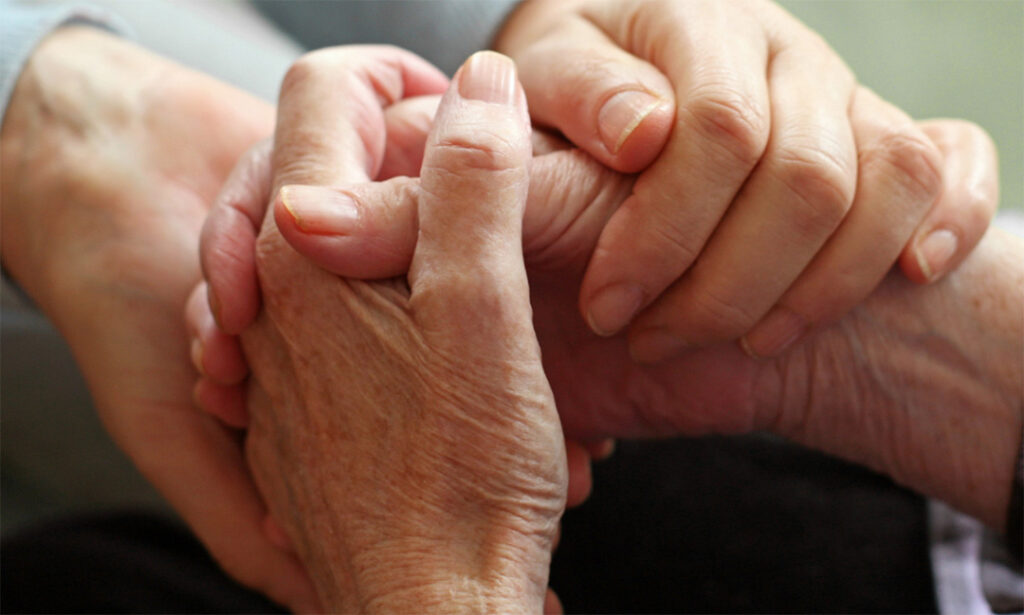 Two pairs of hands holding each other in support