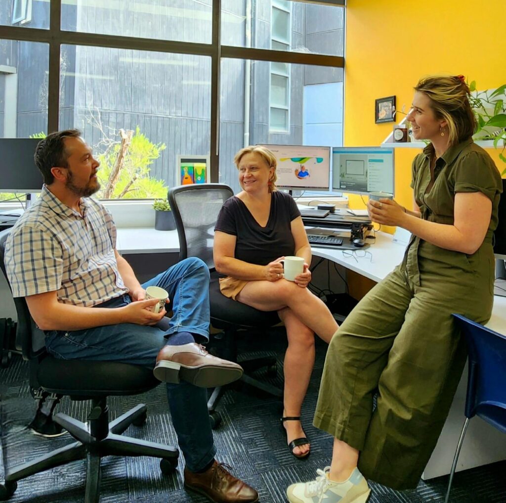 A group of workers sitting around in the office chatting over a cup of tea
