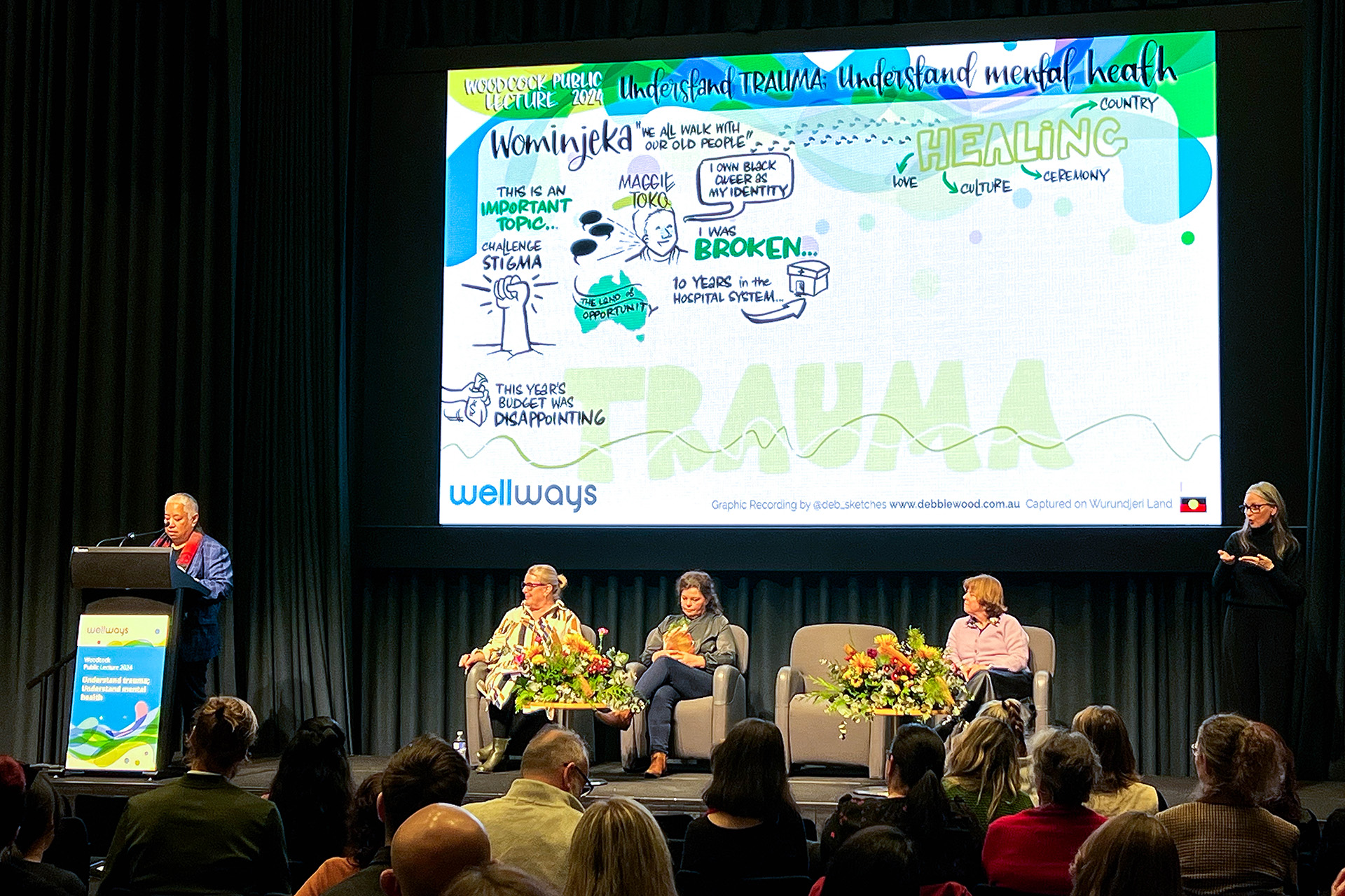 The panel listens to Maggie Toko sharing her story