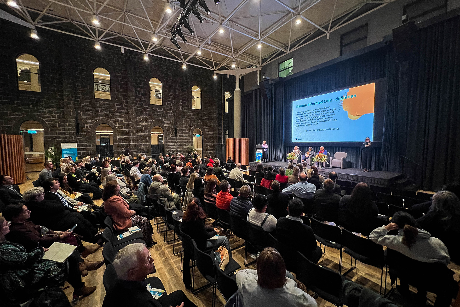 A room full of people watching people speak on stage