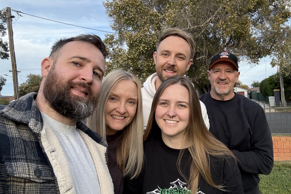 A family closely huddled for a photo smiling widely