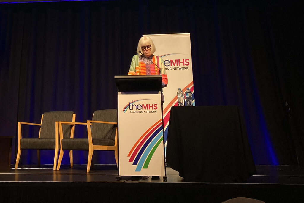 A person on stage behind a lectern.