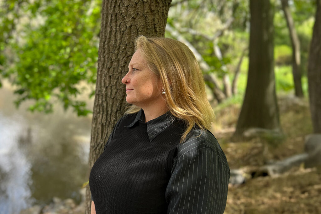 A person standing under a tree looking out over water