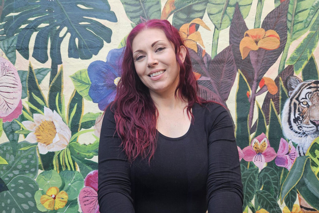 A person in front of a brightly colour wall mural