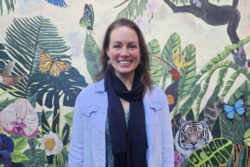 A person in front of a brightly coloured wall mural