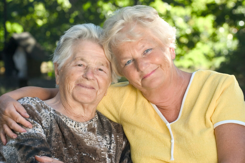 Two older women with their arm around each other.