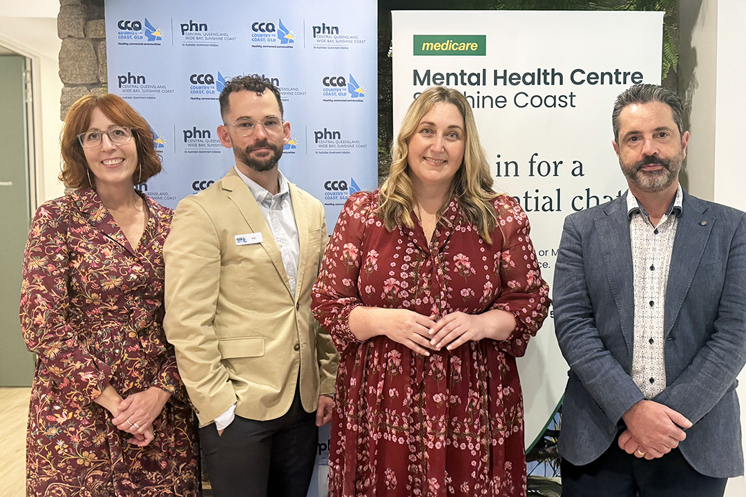 Four people stand in front of Medicare Mental Health Centre and PHN signage for a photo.