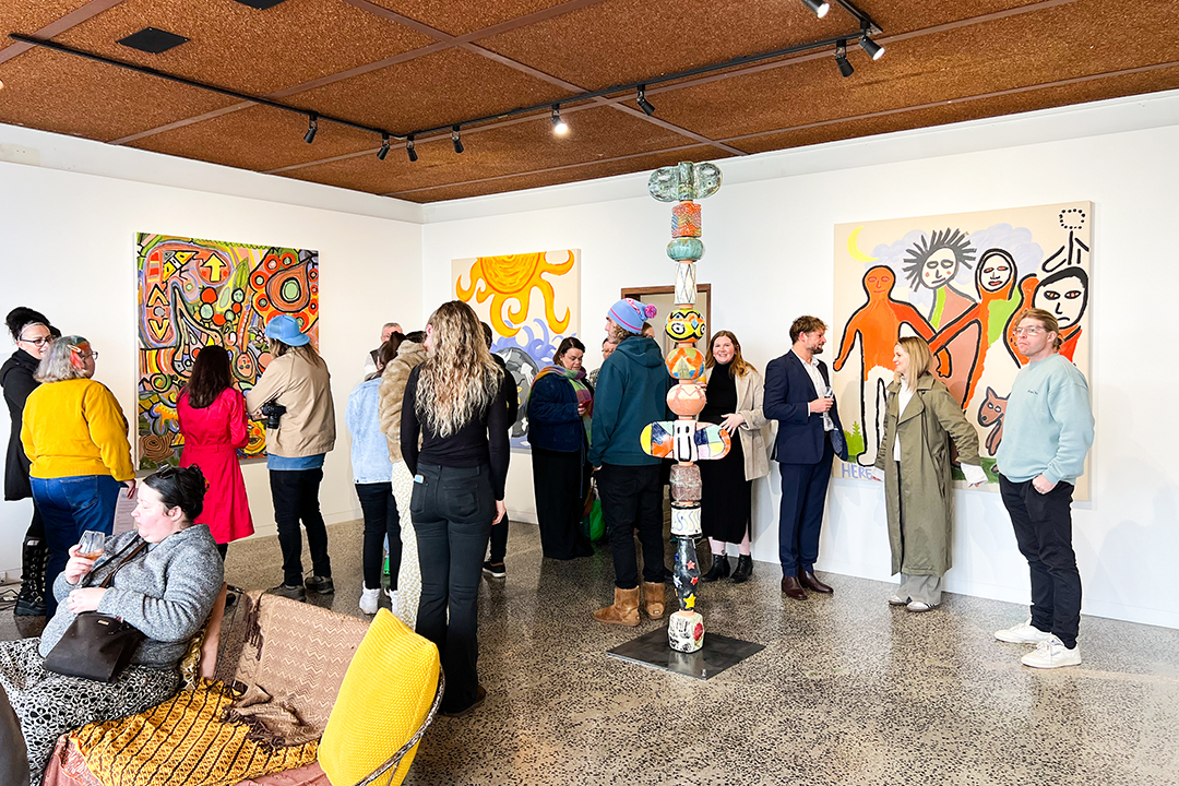 A large group of people mingling at an art exhibition