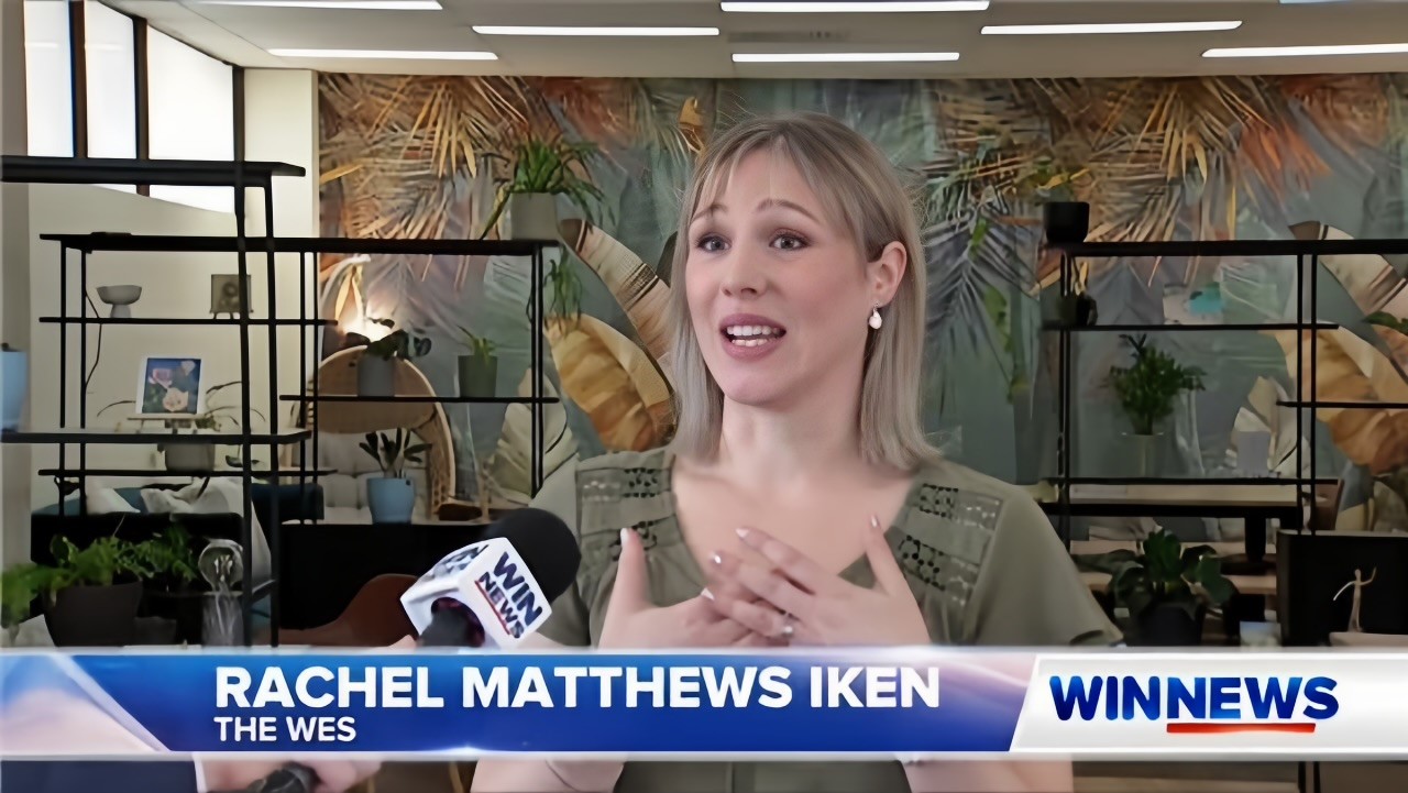 A woman with blonde hair speaks into a WIN News microphone