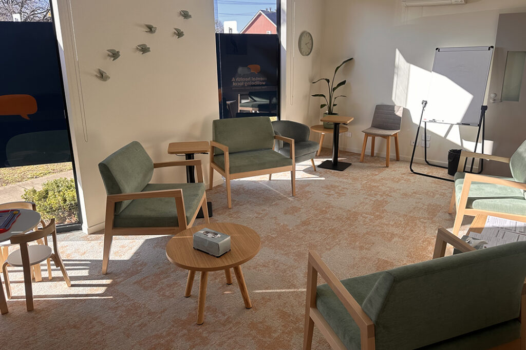 A room with earth tone carpet, chairs, tables and natural lighting