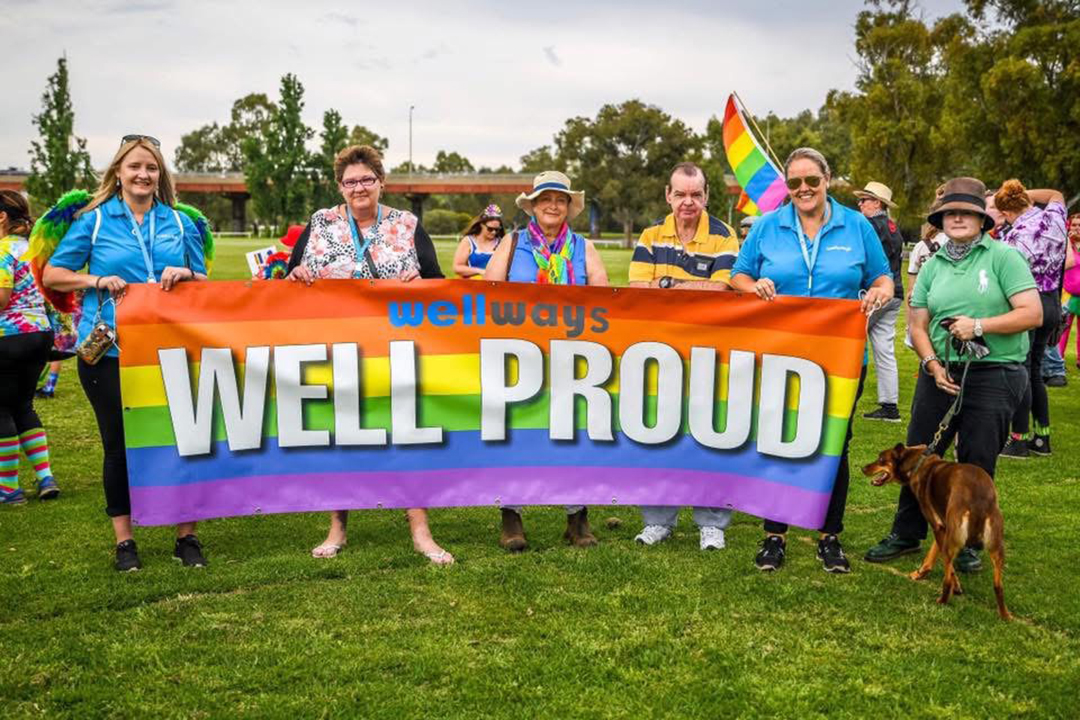 Five people holding a rainbow flag on a field