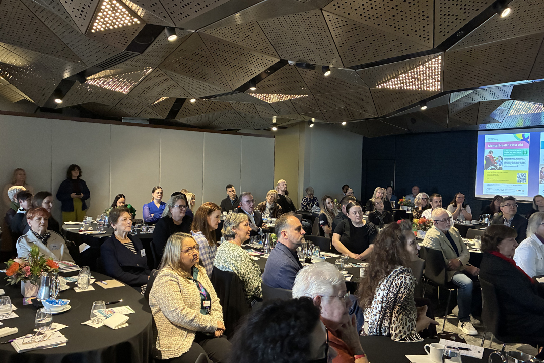 A group of people in a large conference room sitting at tables.