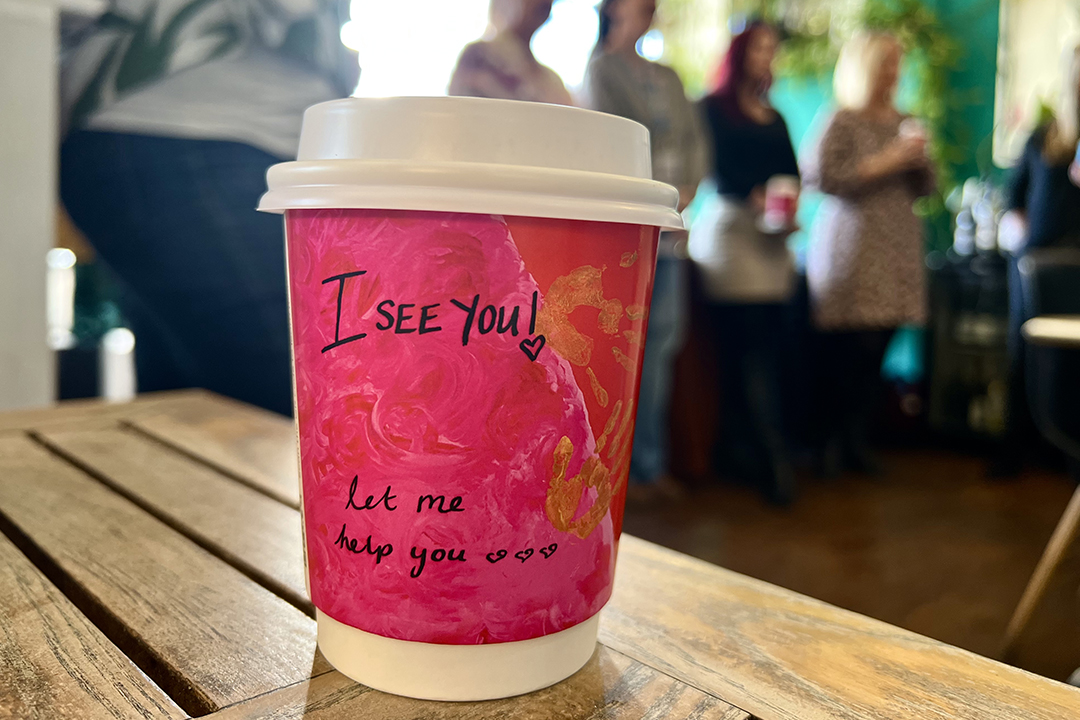 A cup sits on a table with people in the background