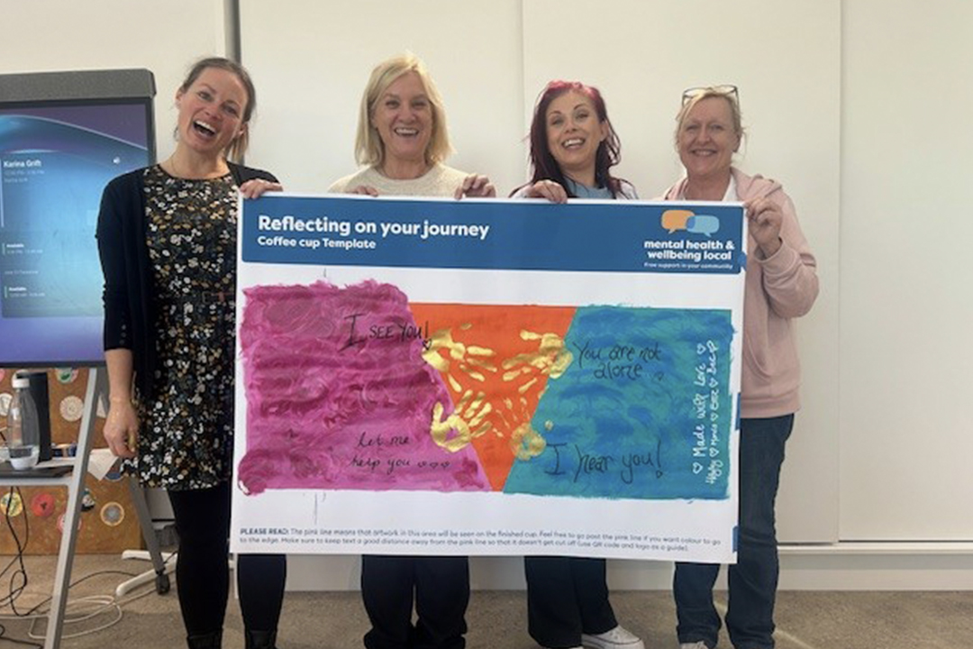 Four people standing side by side holding a large painting