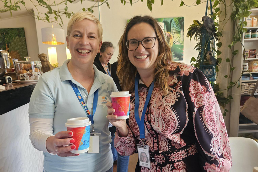 Two people holding bright coloured coffee cups