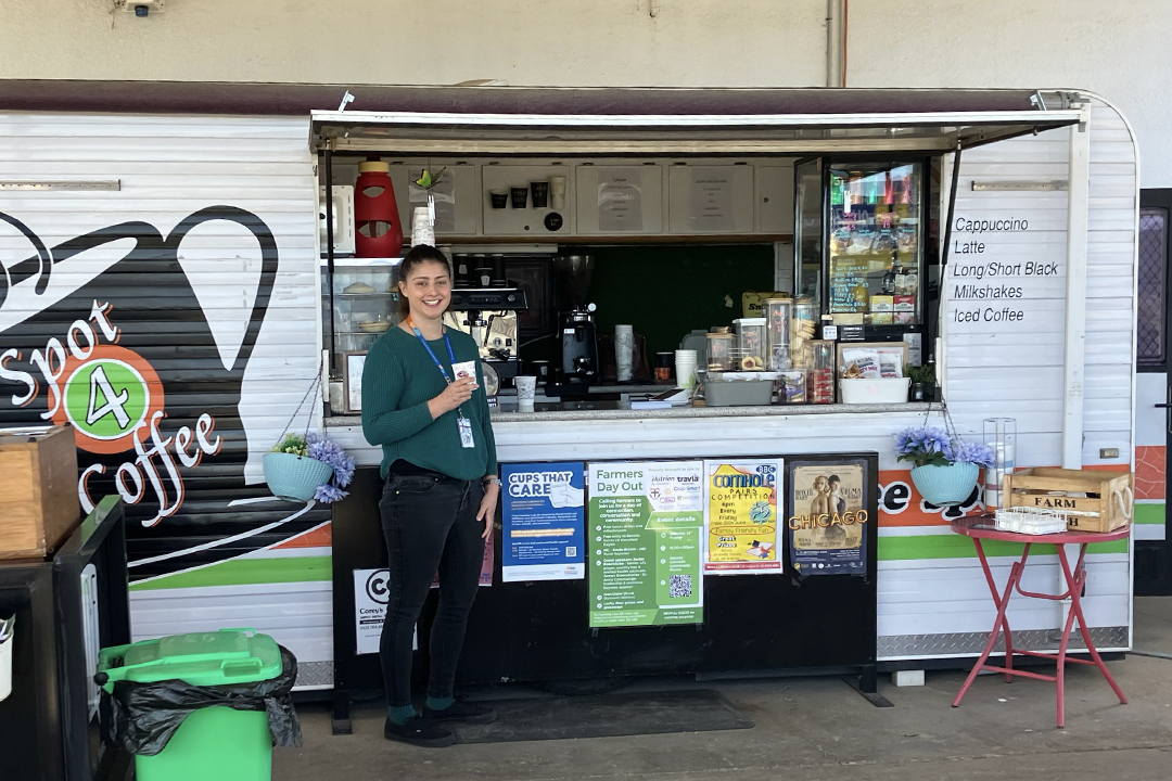 A person stands in front of a caravan converted into a coffee shop