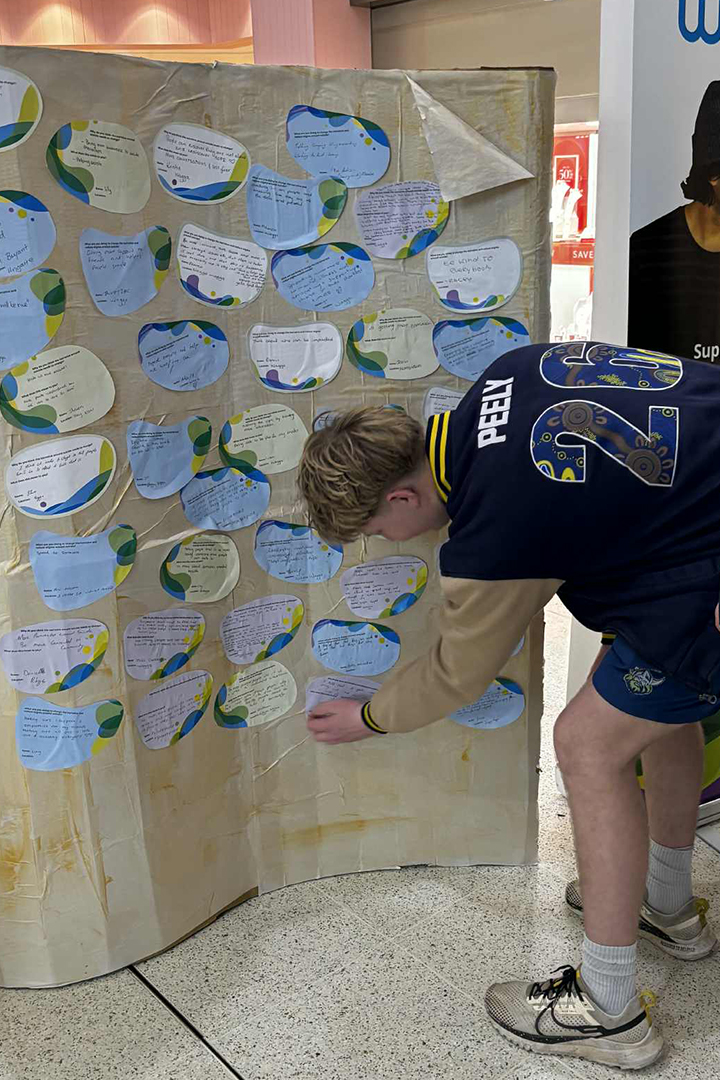 A person bends over to place a cutout piece of paper at the bottom of a display wall.