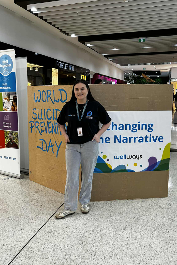 A person in a black shirt standing in front of a sign for world suicide prevention day.