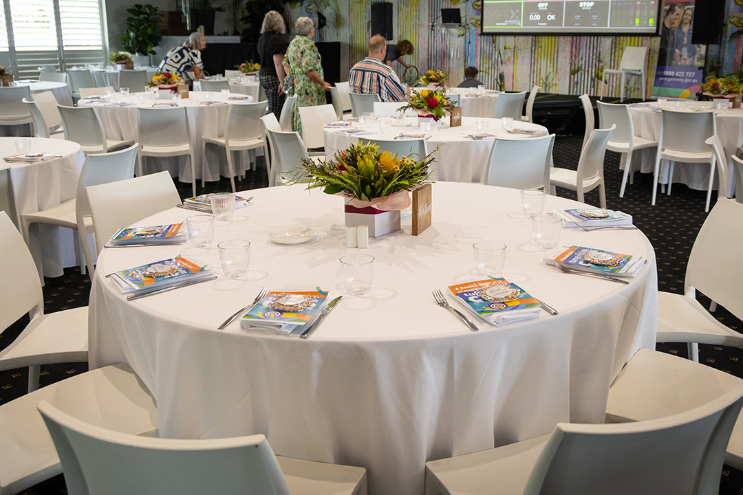 A round table with a white table cloth and center floral arrangment