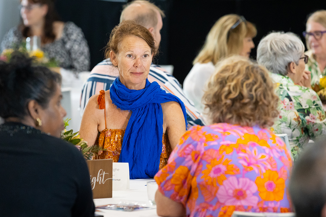 A person with a royal blue scarf speaking with a person wearing a bright pink and orange shirt