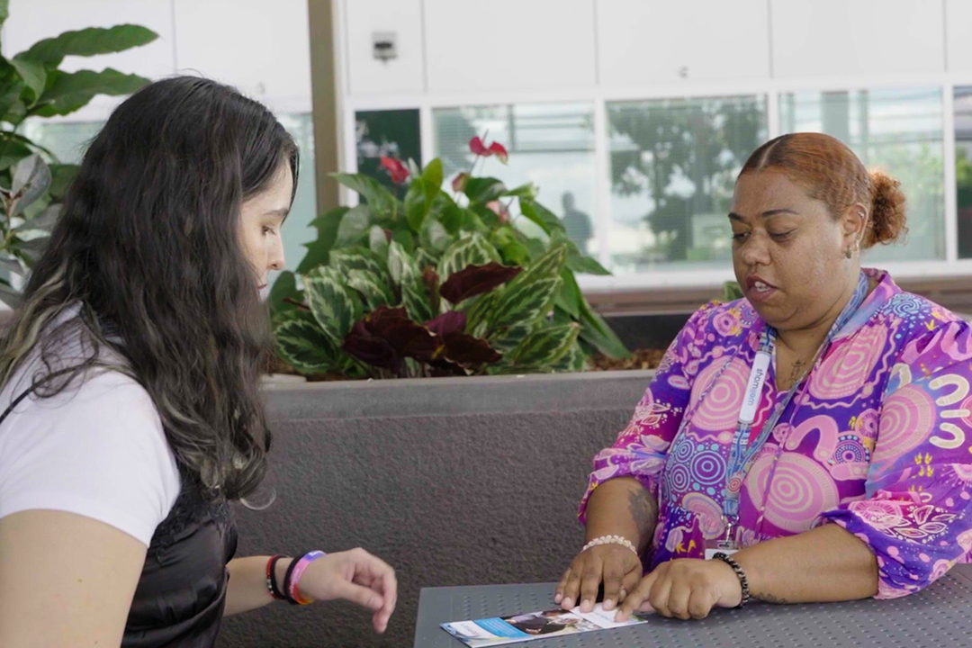 Two people sitting at a table reading a brochure.