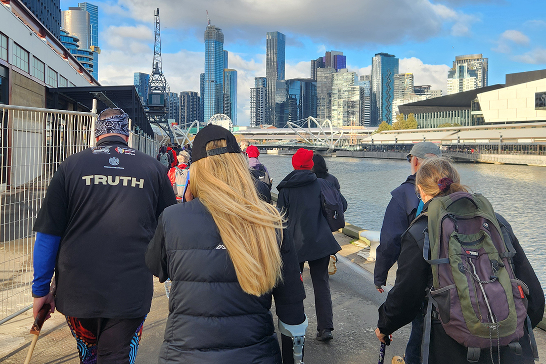 A group of people walking along the Yarra River towards Melbourne CBD