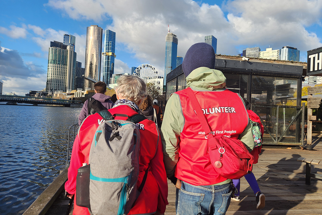 A group of people walking along the waters edge in Melbourne