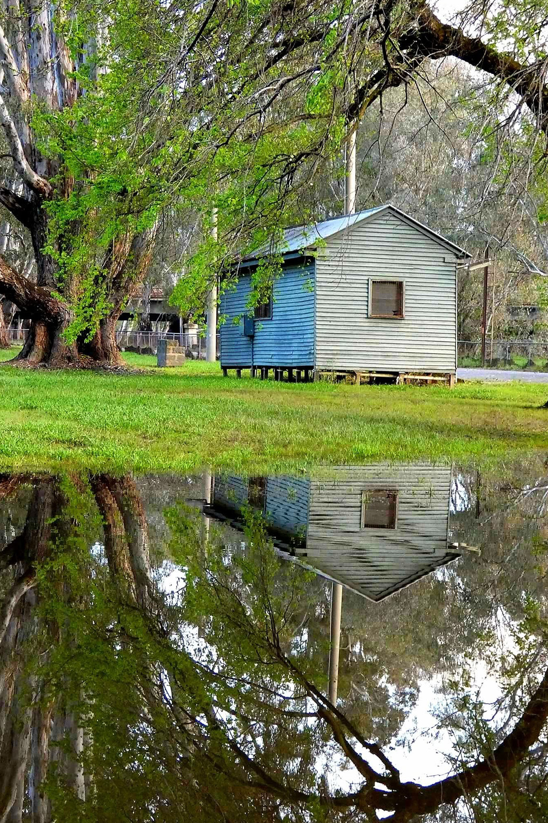 A small building surrounded by trees and calm water