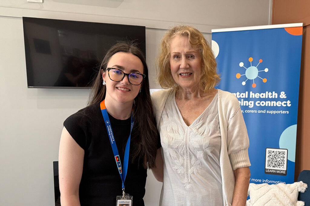 Two people, a person wearing a dark shirt on the left and a taller person in a light shirt on the right.