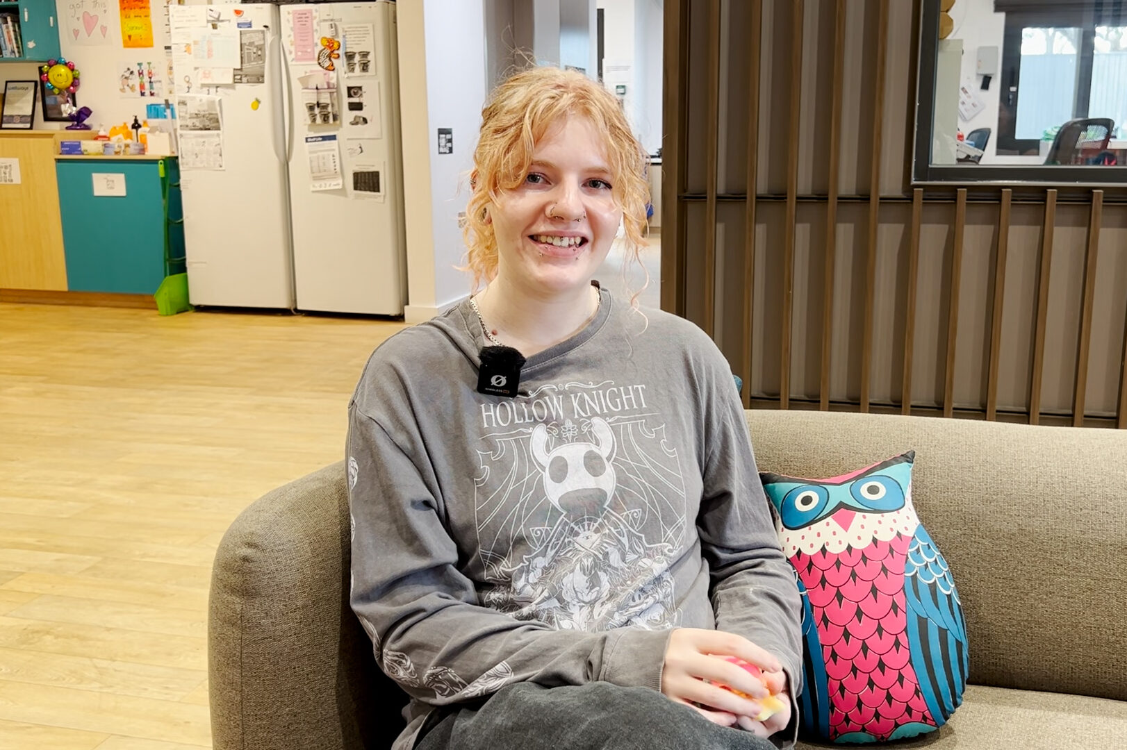 A person sitting on a couch next to a pillow in the shape of an owl