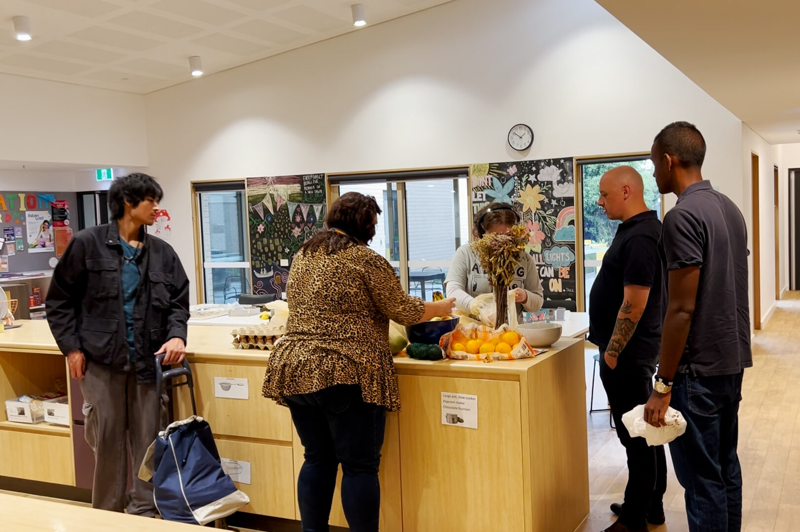A group of people gathered around a kitchen island preparing food