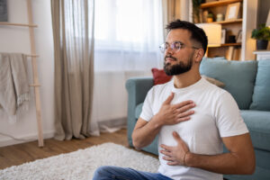 Man sitting in living room with eyes closed doing breathing exercises 