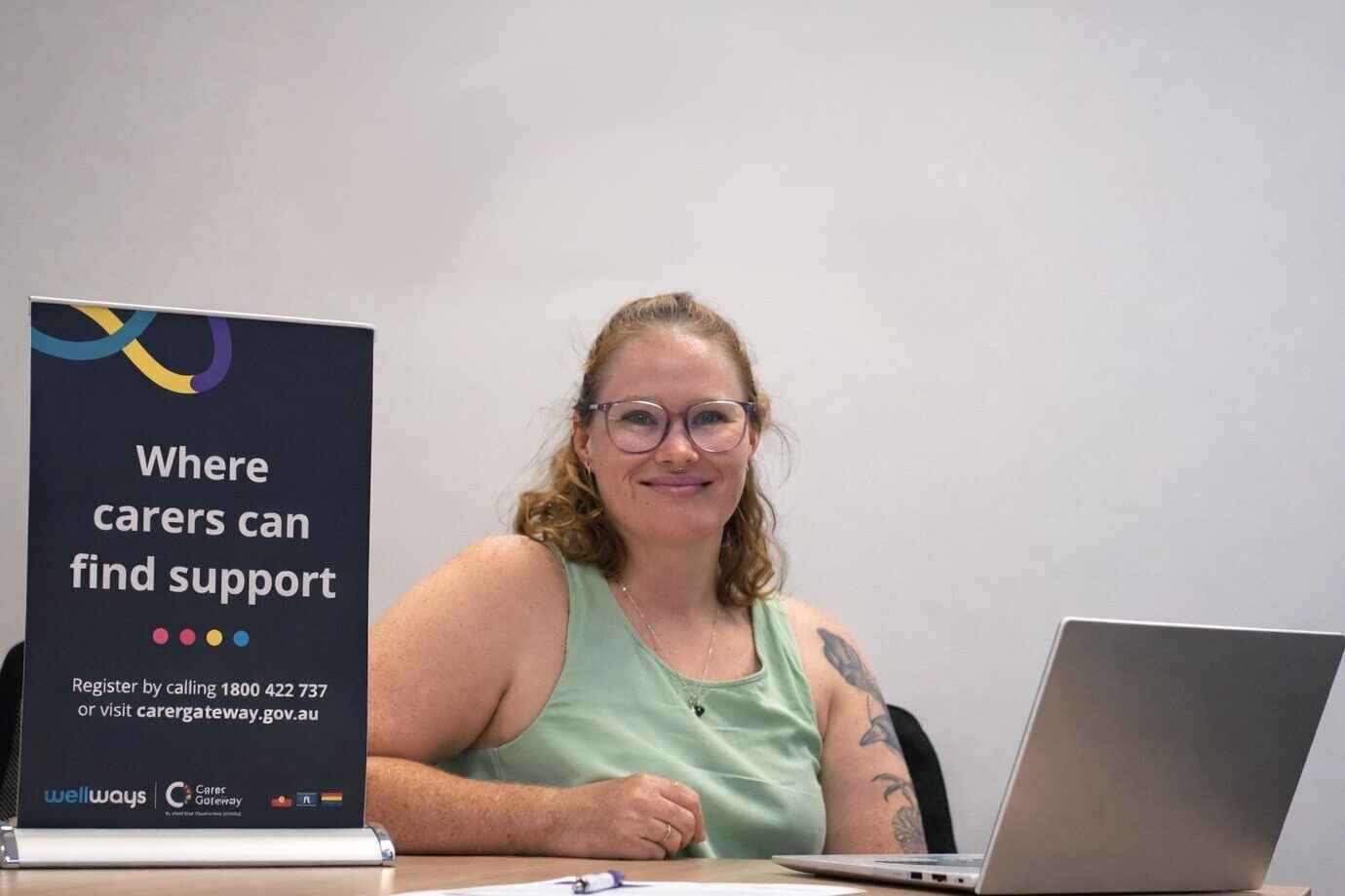 Young woman in an office with a laptop and banner