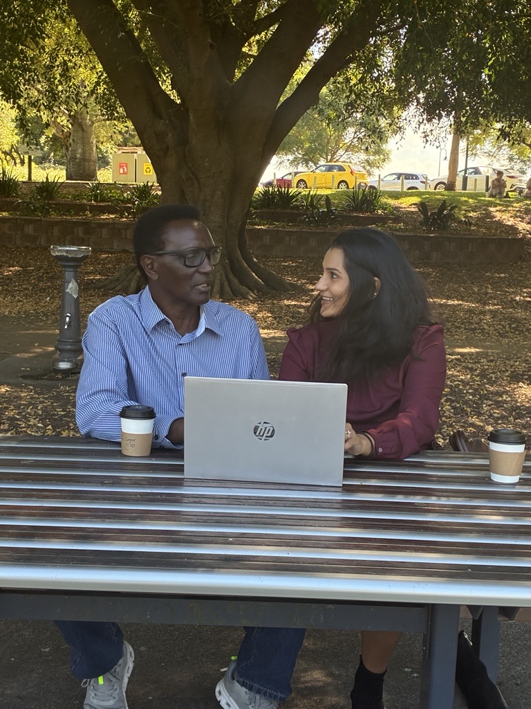 Two people in a park with a laptop