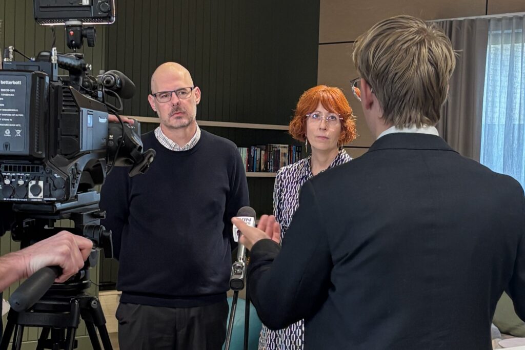 A media crew filming an interview with two people in a large room