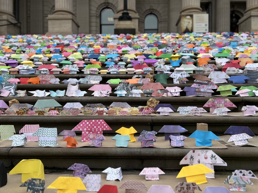 Lots of colourful small origami houses on the steps of Victoria's Parliament House