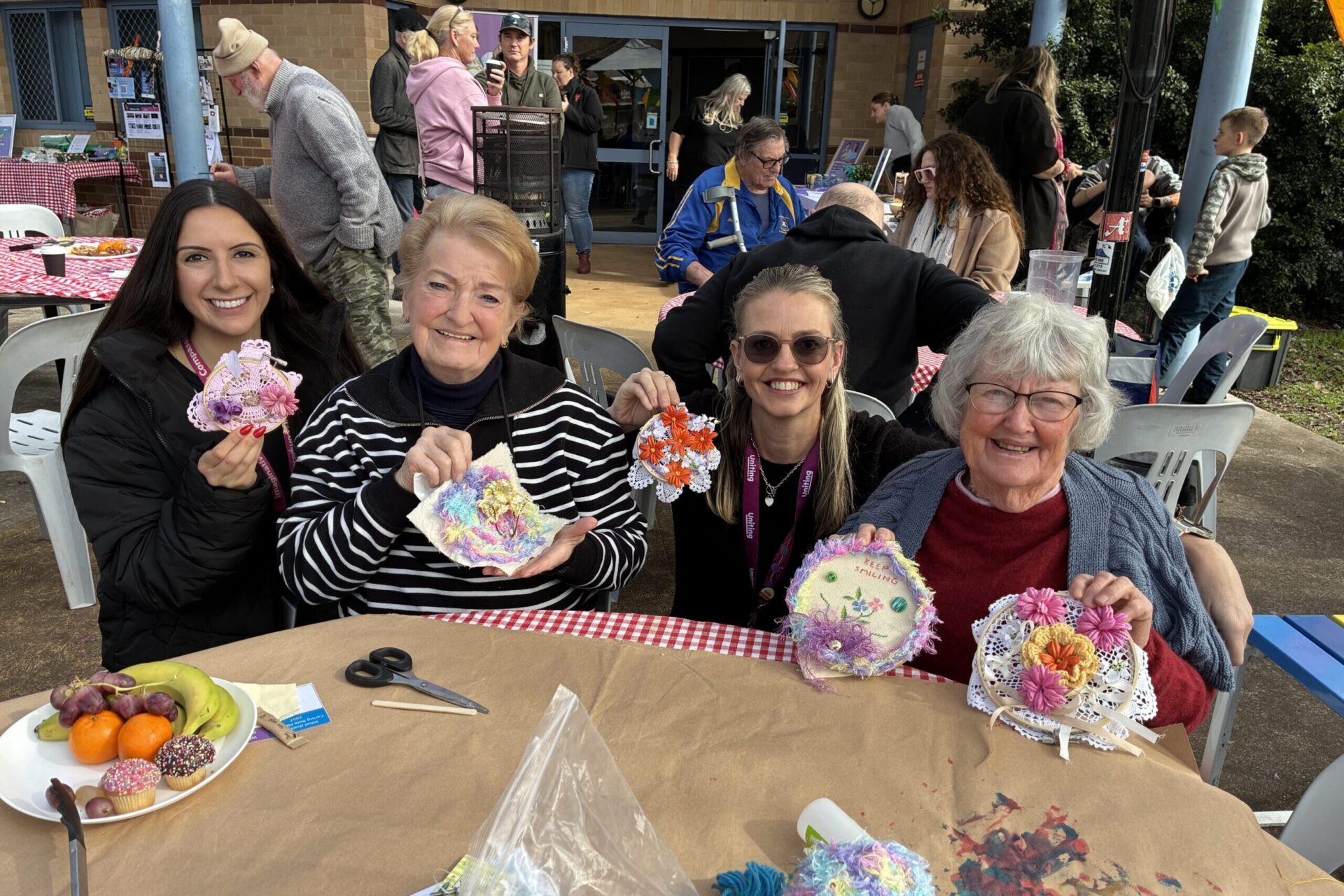 Four people smiling and holding crocheted pieces