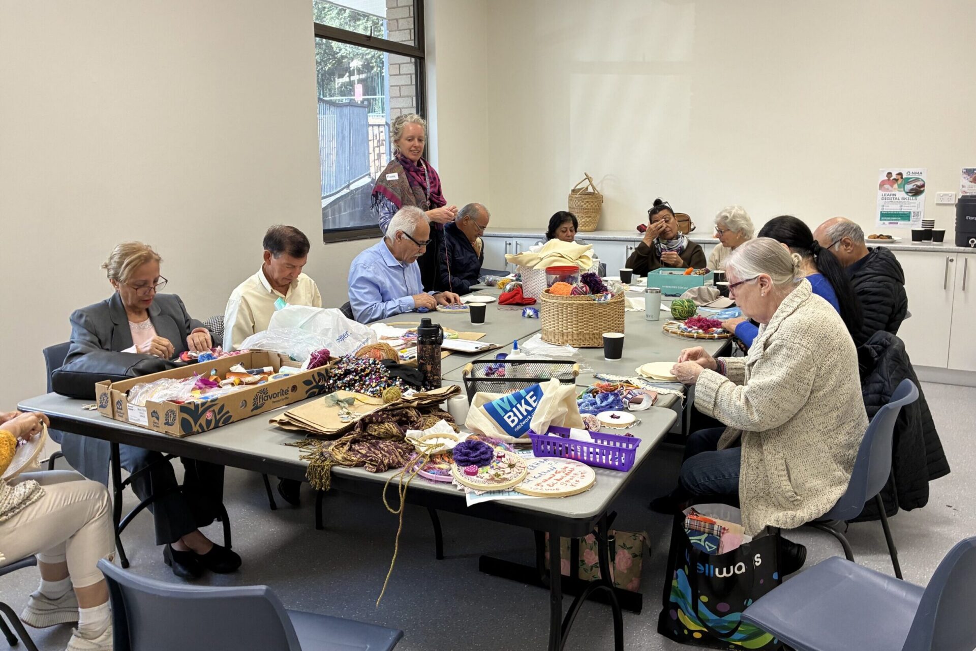 A group of people in an office room sitting around a table doing crafts