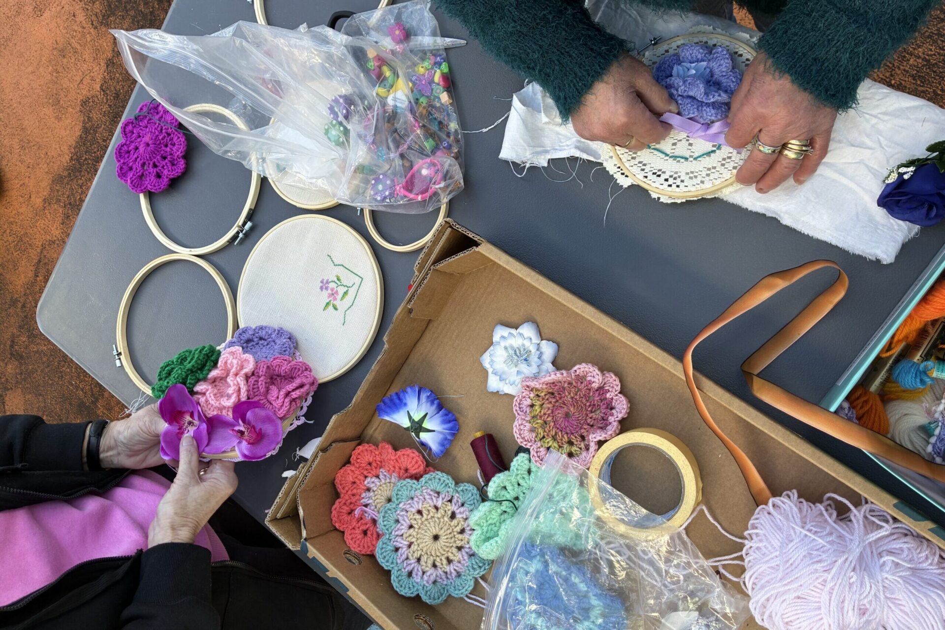 Two pairs of hands holding embroidery hoops