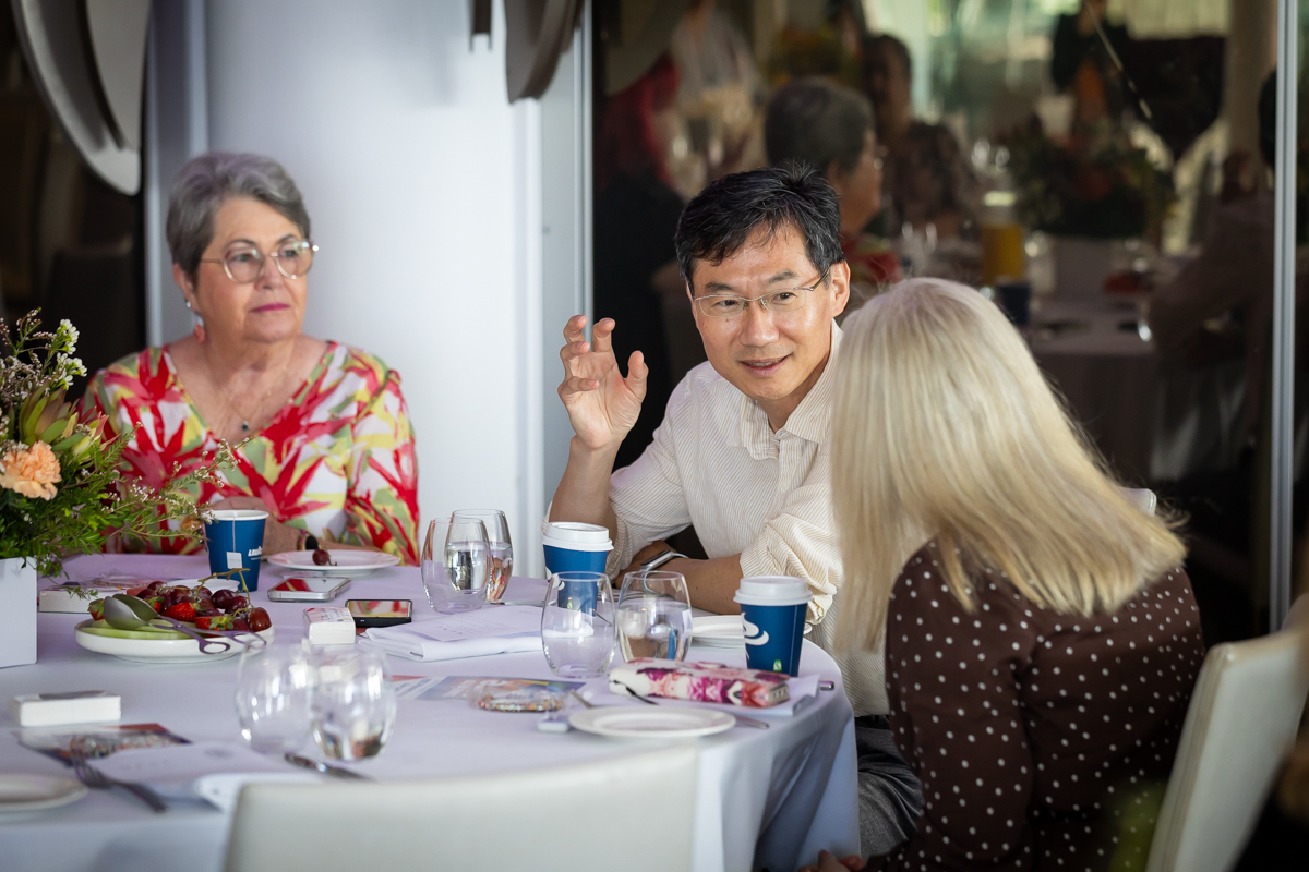 Three people talking to each other around a table