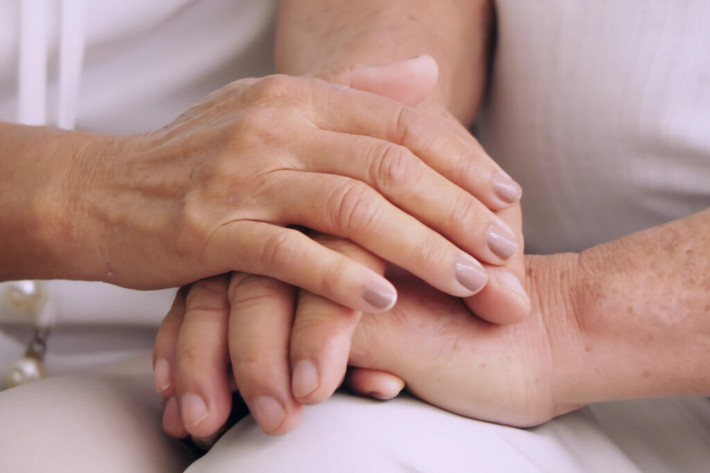 Two pairs of hands held together on a persons lap