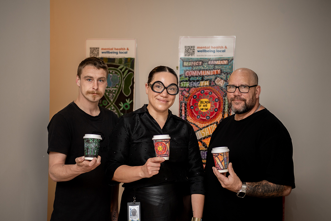 Three people, each holding a coffee cup with printed artwork.