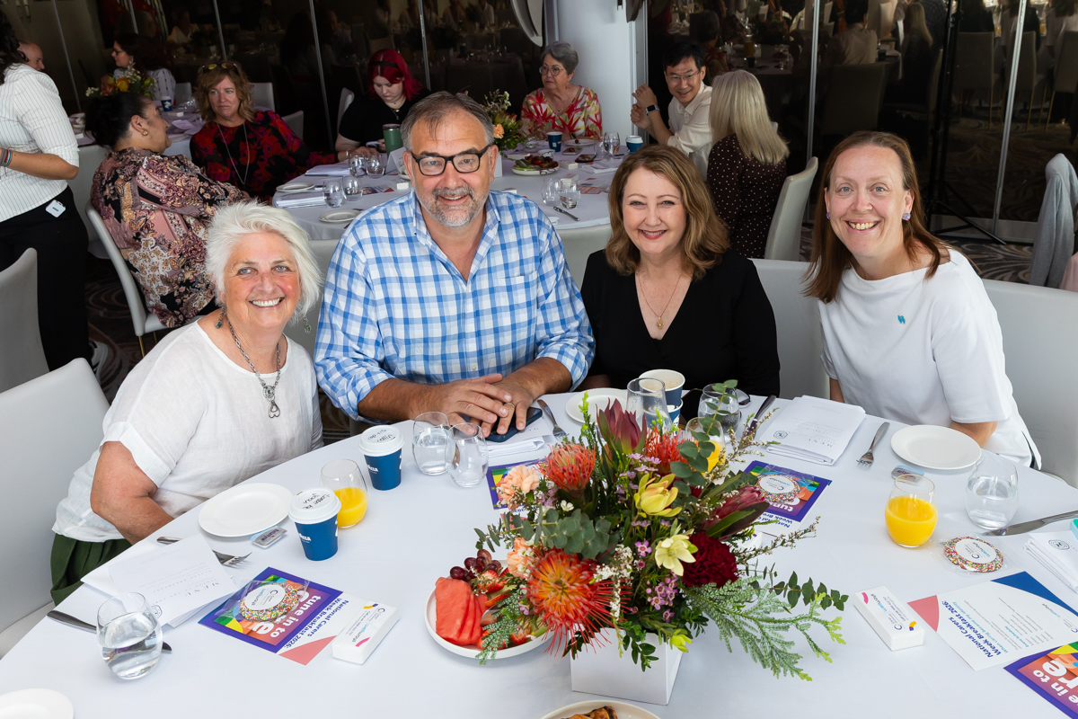 Four people sitting at a table posing for a photo.